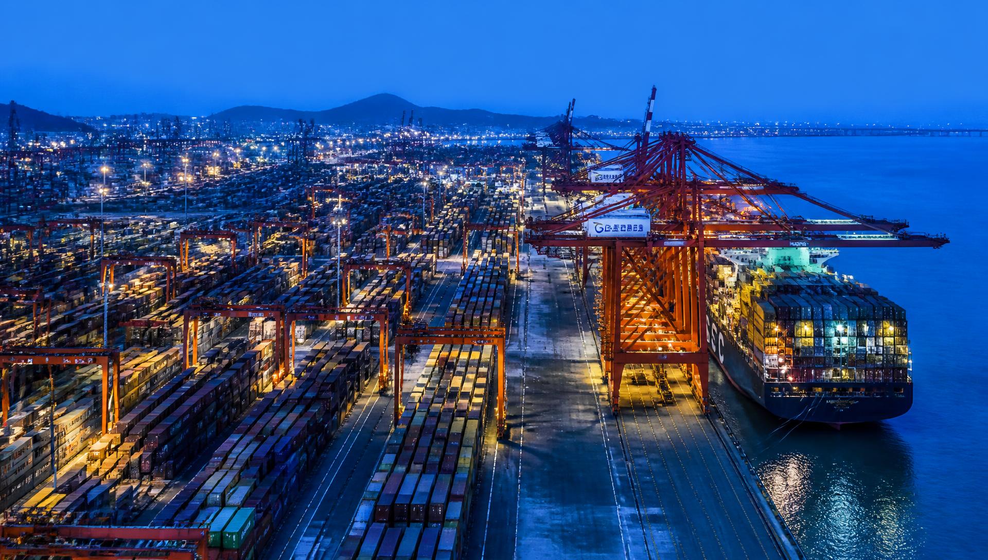 Container ship being loaded with cargo at a Chinese port at blue hour
